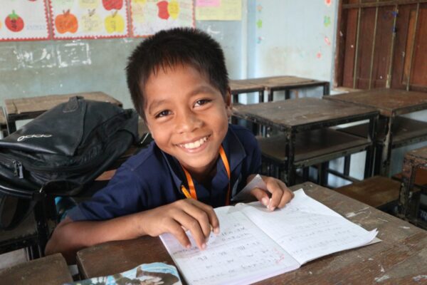 Boy sits at a desk in a Cambodian school