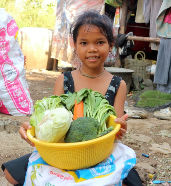Girl with basket of vegetables and large bag of rice