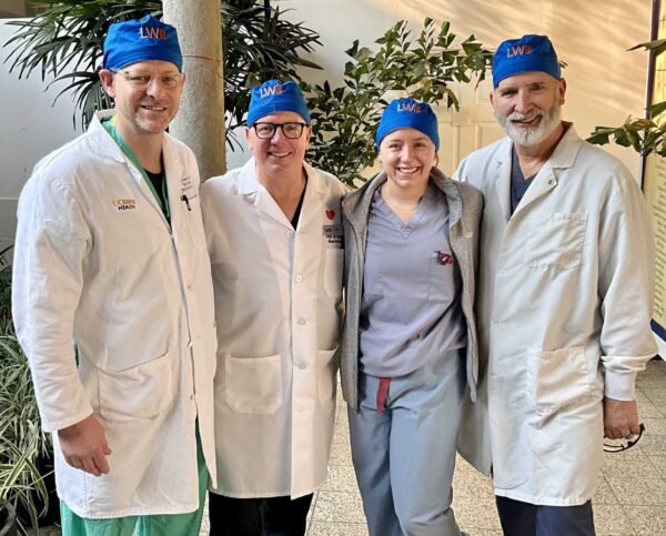 Four surgeons stand together in their surgical caps